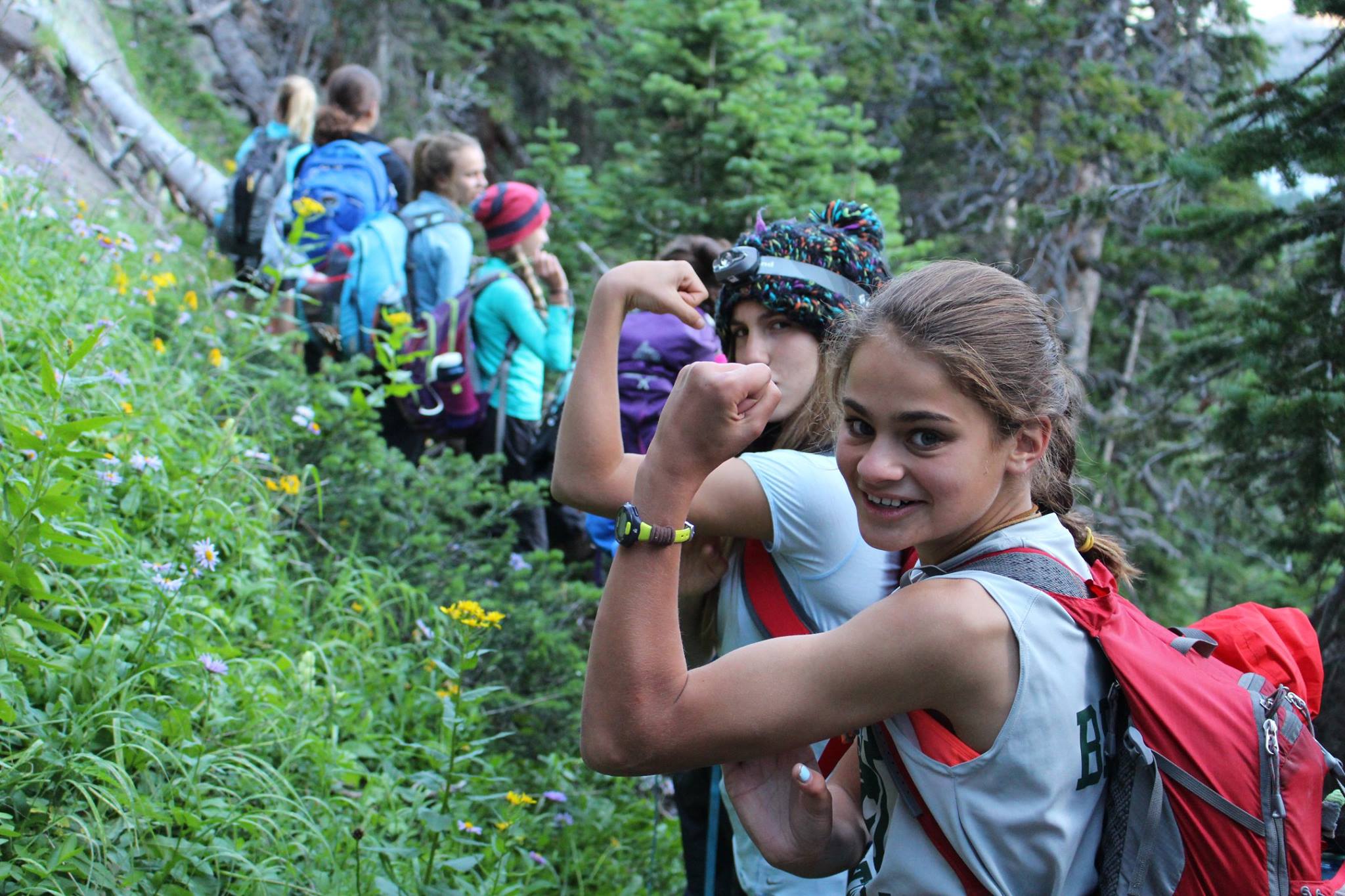 young girls flexing arms while on a hike in colorado